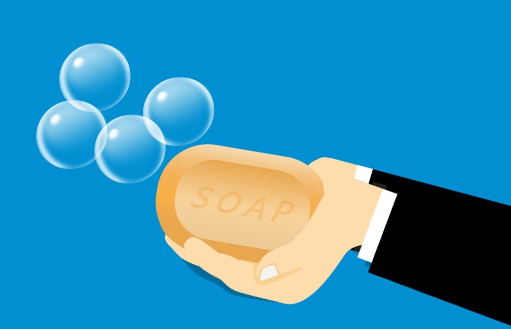 Hand holding a bar of soap with bubbles. Is it okay to use hydrogen peroxide to clean sex toys?