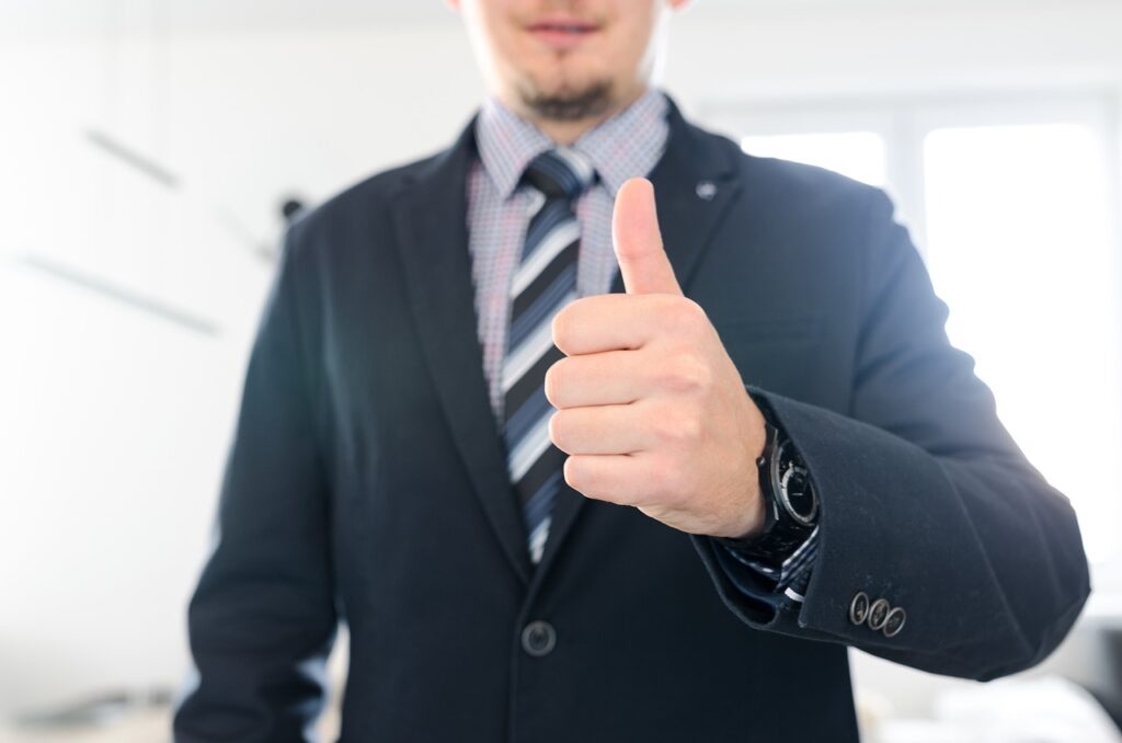Wearing a butt plug to work, photo of a man, dressed in work attire, giving the thumbs-up