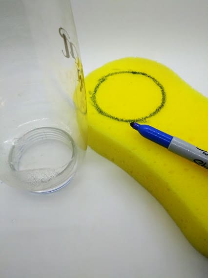 DIY penis pump; photo of step 2 tracing the mouth of the water bottle onto a large, yellow sponge.