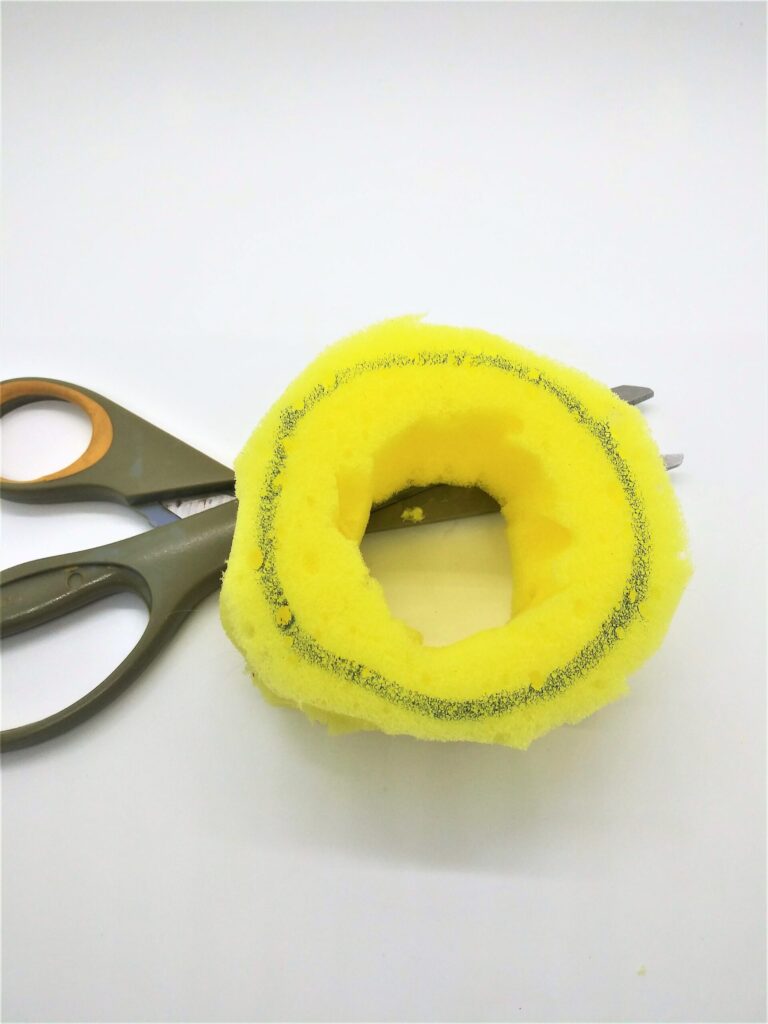 Homemade penis pump tutorial; photo showing step 7 and the center being cut out of the circular piece of sponge.