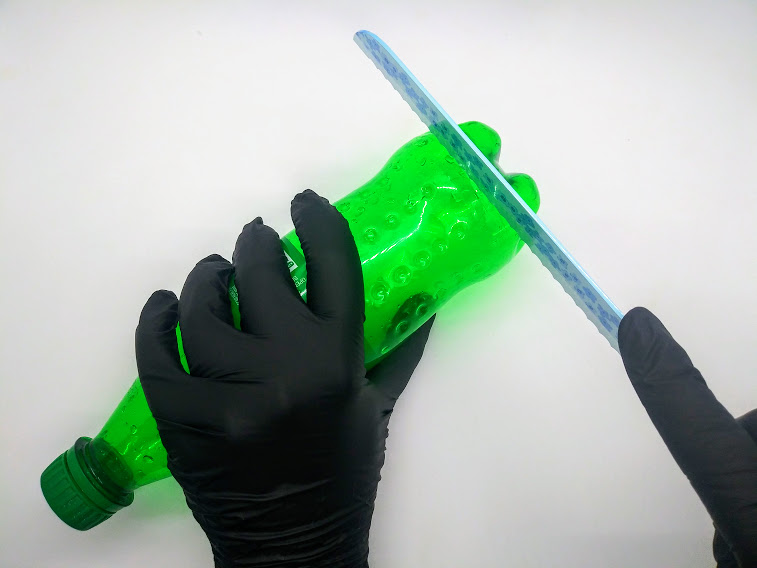 Homemade penis pump tutorial; photo of step 1 showing the bottom of the soda bottle being cut off with a serrated knife.