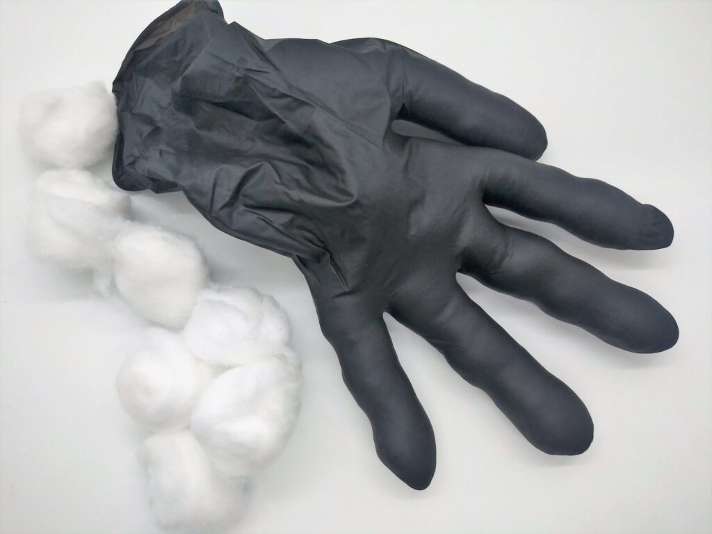 Homemade anal sex toys using a medical glove. Photo of a black medical glove with all fingers stuffed with cotton balls.
