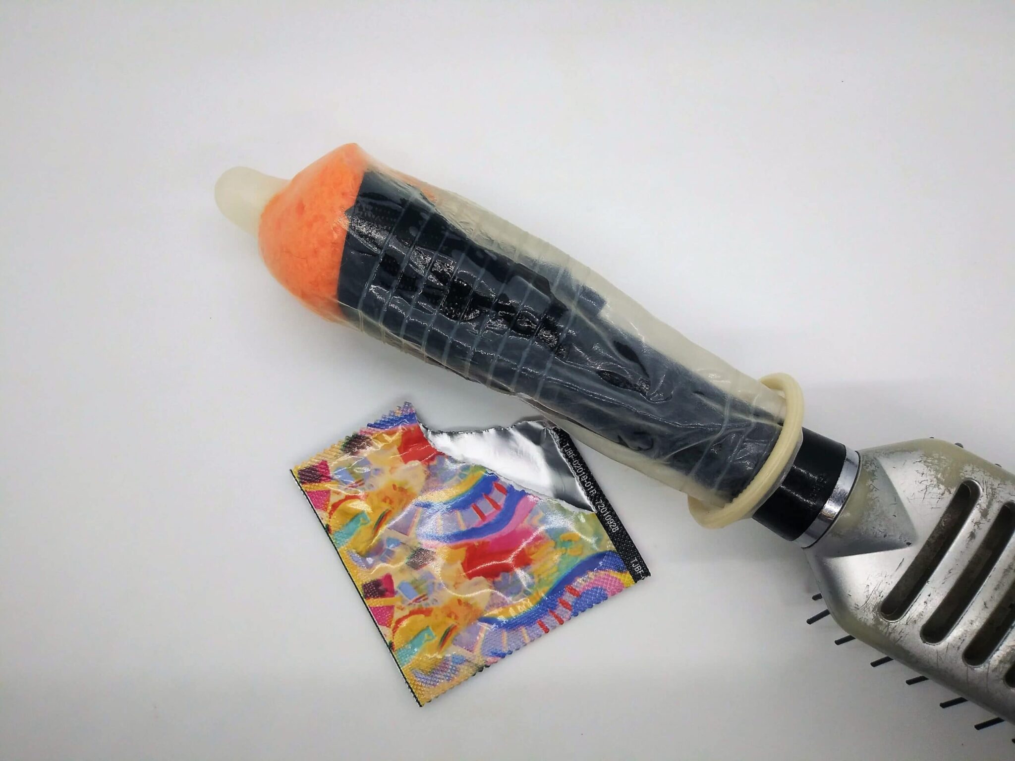 DIY anal sex toy from a hairbrush, photo of the hairbrush handle covered with a condom.