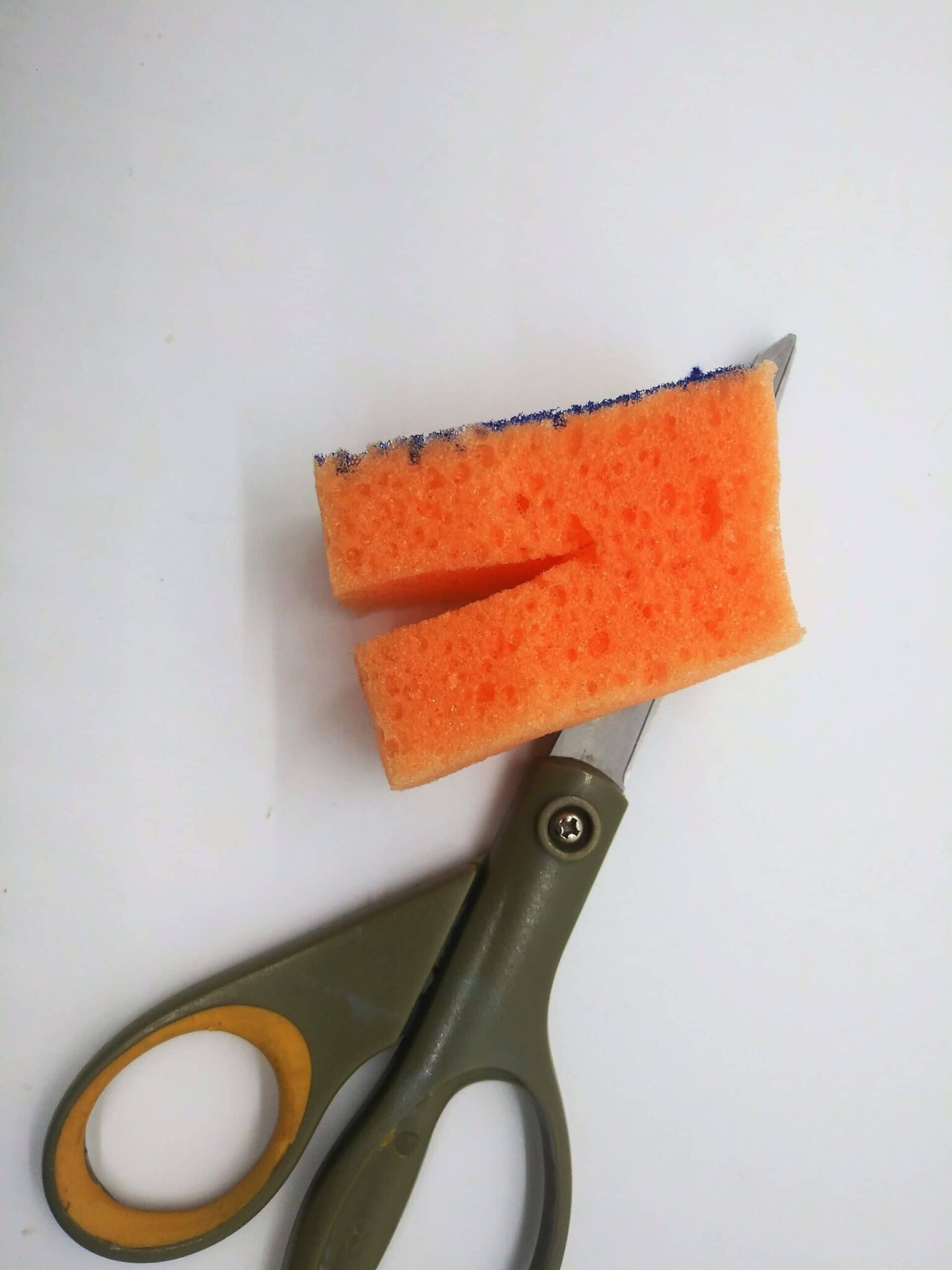 DIY anal sex toy from a hairbrush, photo of the small sponge piece being cut with scissors.