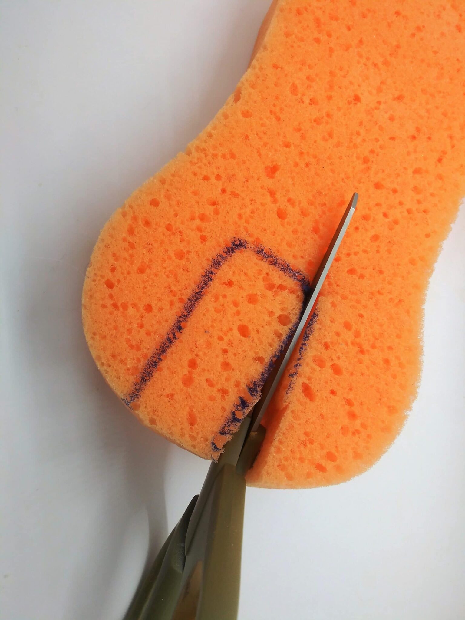 How to made an anal toy from a hairbrush. Step 3 photo of an area being cut from a sponge with scissors.