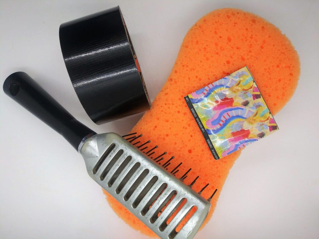 Homemade hairbrush sex toy, photo of a hairbrush, sponge, tape and condom.