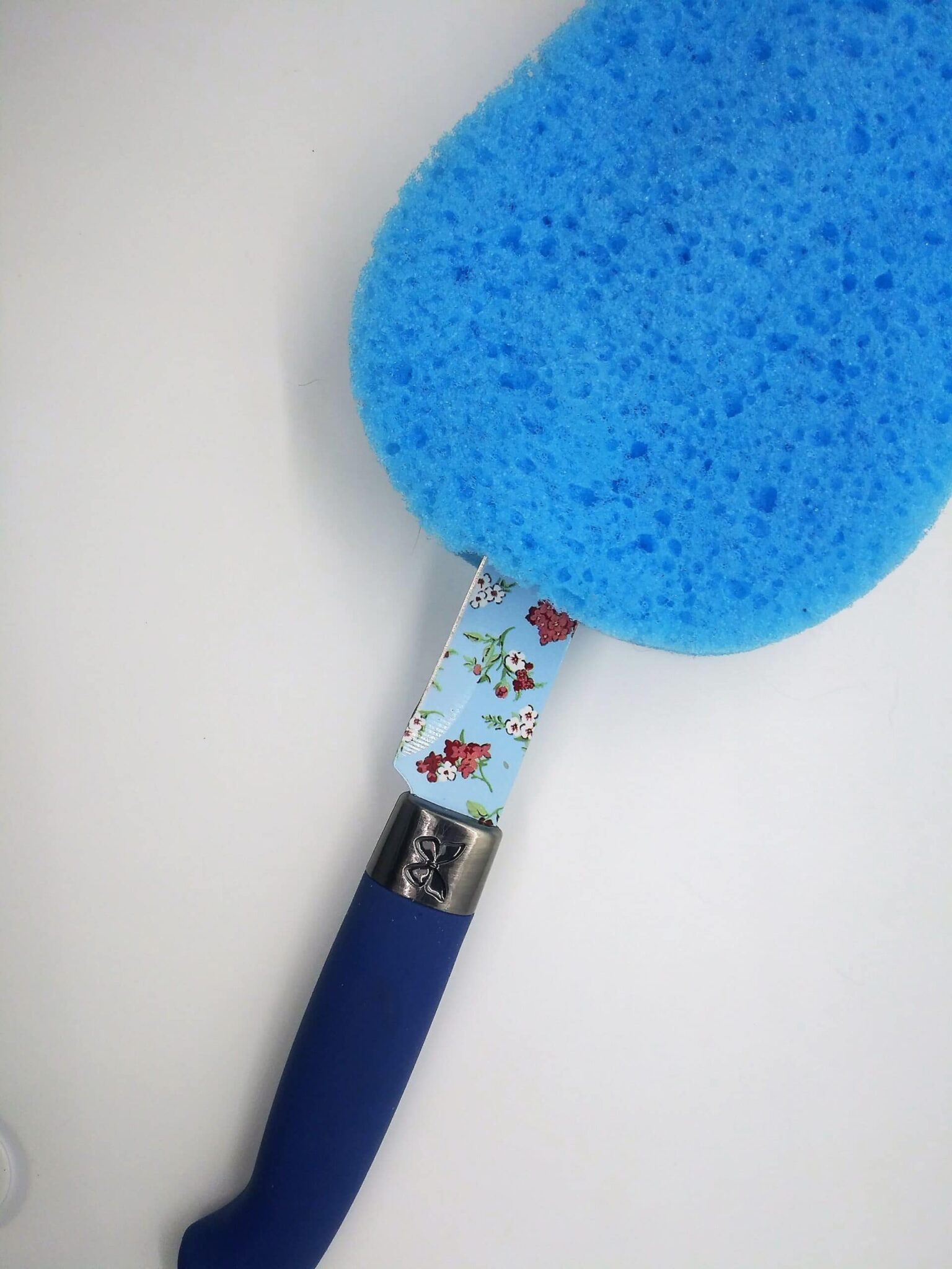 DIY anal sex toys, making a toy from a sink plunger. Photo of a large, blue sponge with a kitchen knife cutting a slit in the bottom.