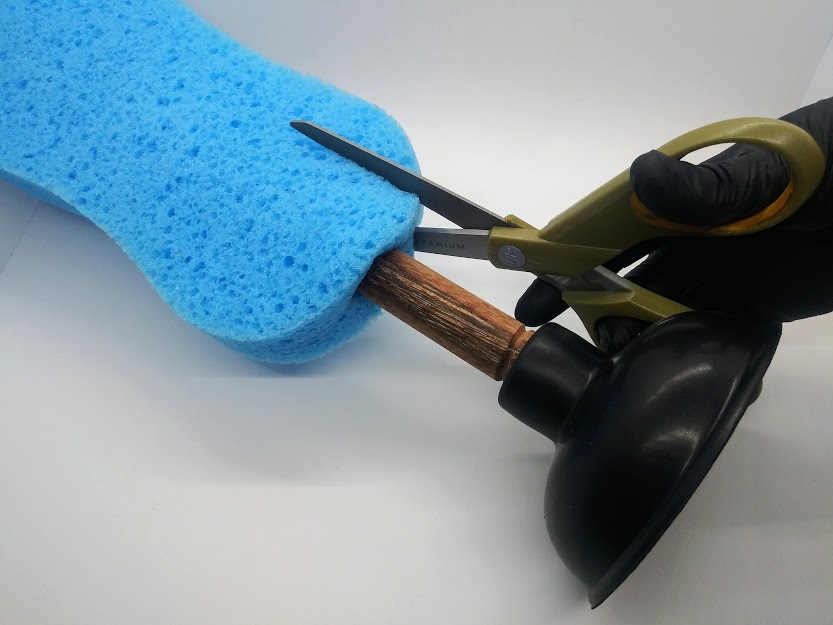 DIY anal sex toys made from a sink plunger, Photo of a sink plunger with a large sponge covering the handle and scissors being used to trim off the excess sponge on either side.