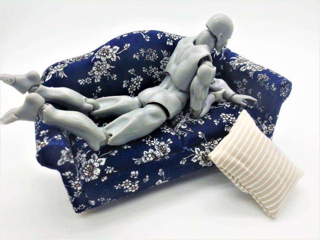 Photo of a male figure using a masturbator upright, between sofa cushions.