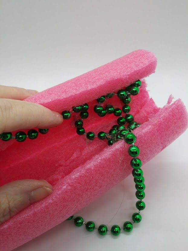 DIY Fleshlight using a pool noodle. Showing how to place bead strands inside the tube with hot glue.